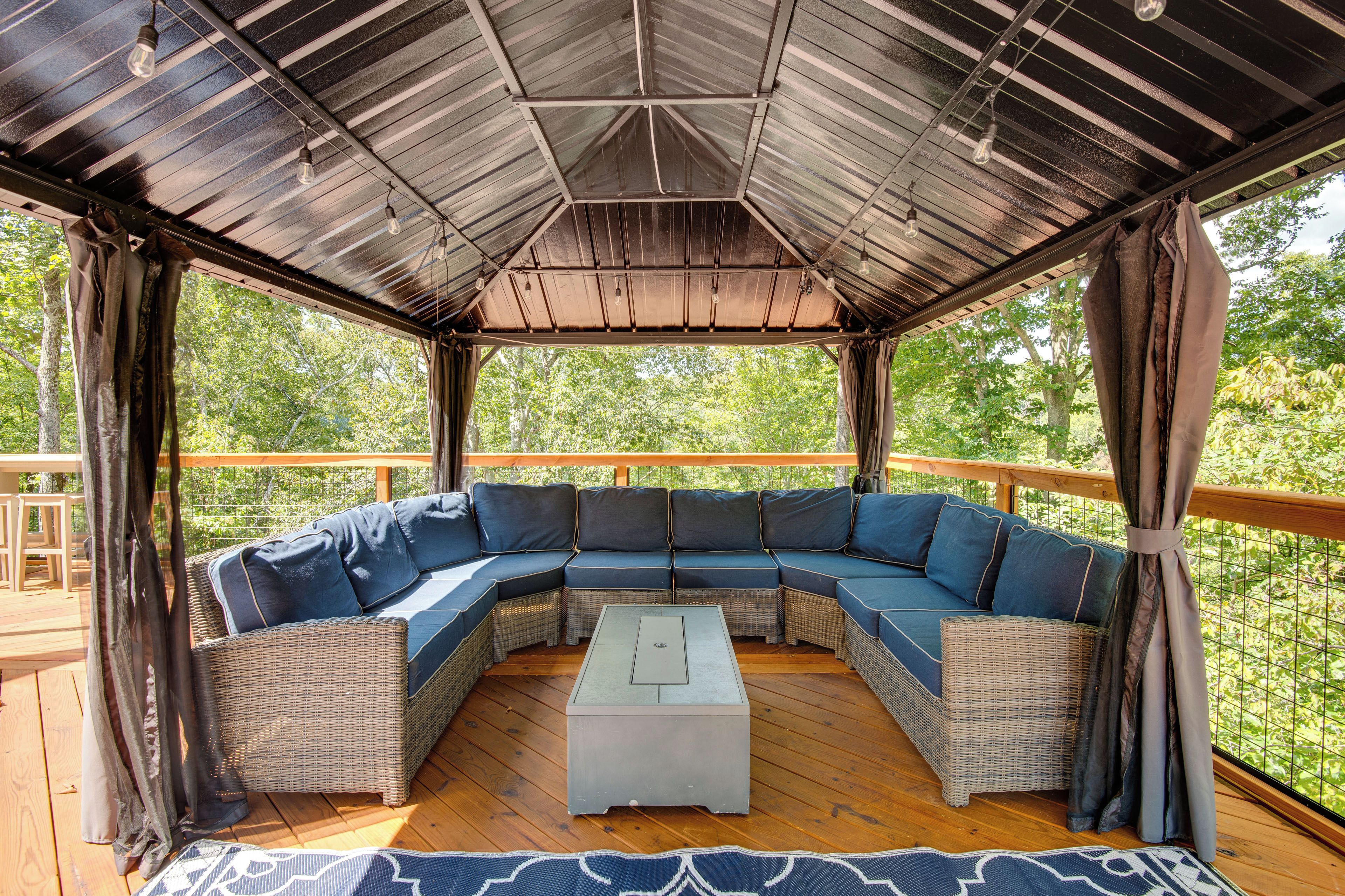 A covered outdoor seating area with a curved sofa and a central coffee table.