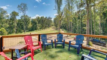 A deck with outdoor seating and a view of a forested area.