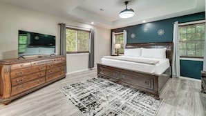 A bedroom with a wooden dresser, a bed with a white comforter, a patterned rug, and a ceiling fan. - Patio, Porch + Fire Pit! Family Home By Branson (Rockaway Beach)