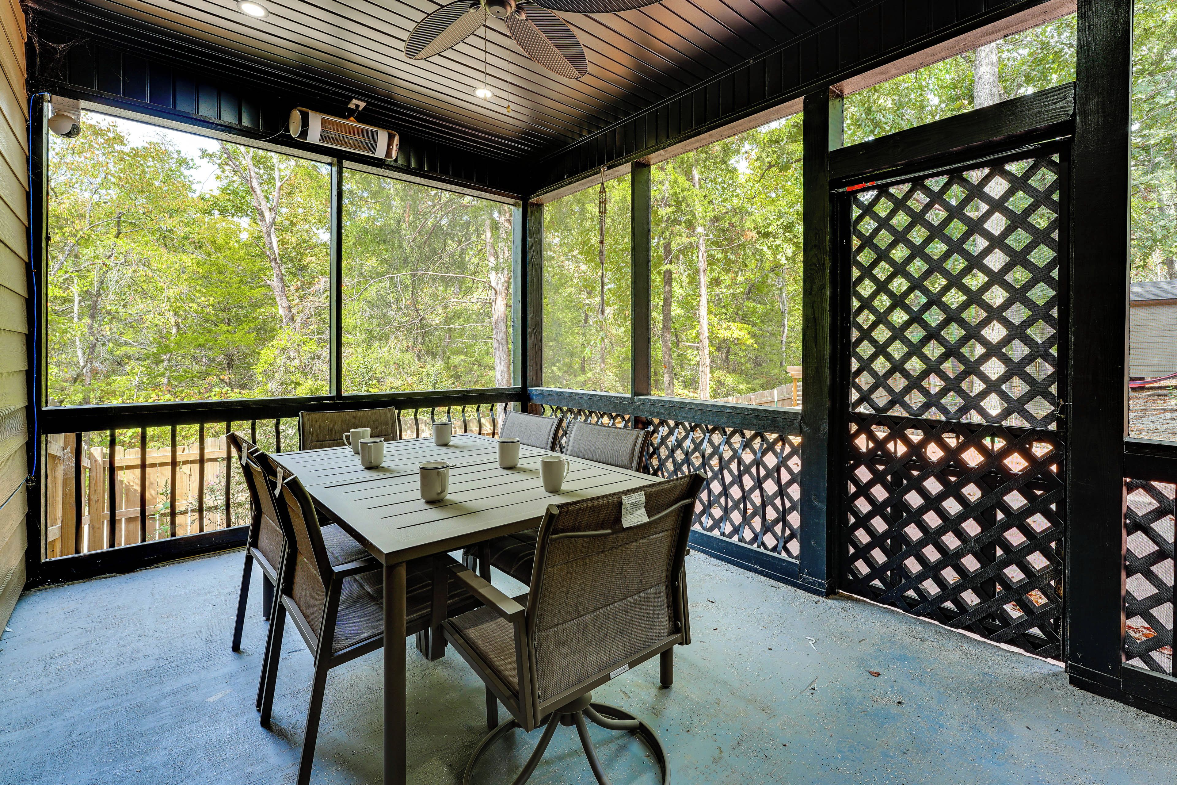 A covered outdoor seating area with a table and chairs, large windows, and a lattice screen.