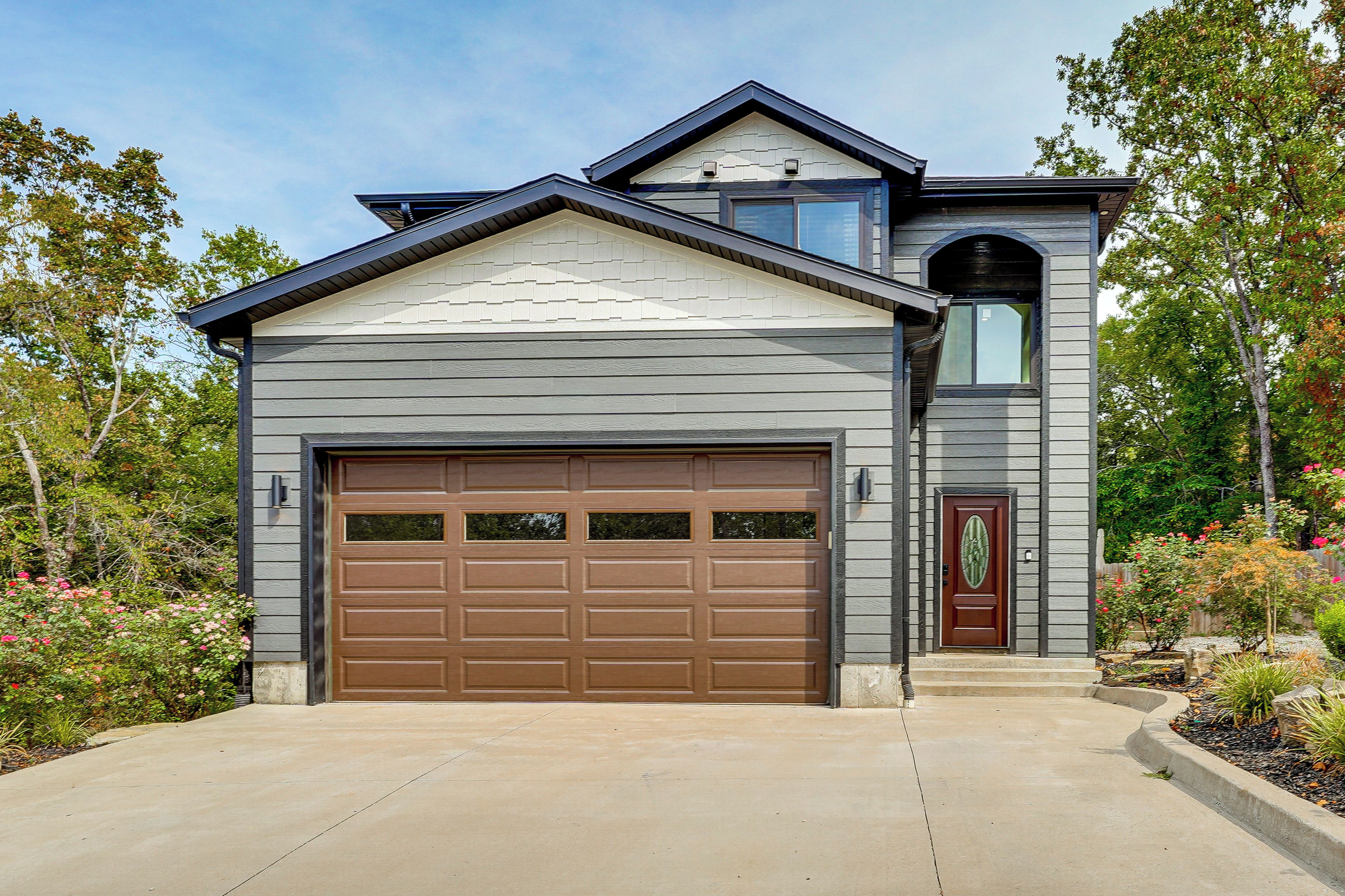 A modern two-story house with a large garage door, a front entrance with a door, and a small window above the garage.