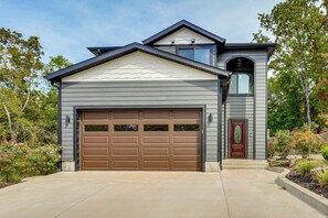 A modern two-story house with a large garage door, a front entrance with a door, and a small window above the garage.