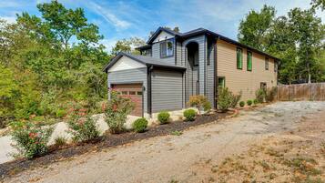A two-story house with a garage, surrounded by a gravel driveway and a wooden fence.