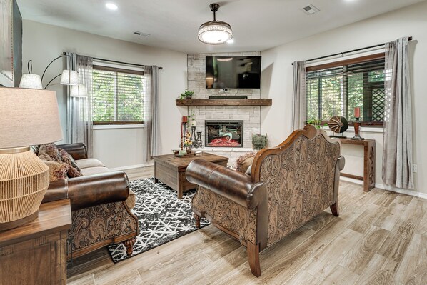 A living room with a fireplace, a sofa, a coffee table, and a television mounted above the fireplace.