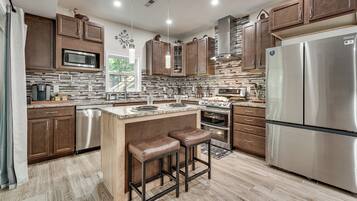 A modern kitchen with stainless steel appliances, wooden cabinets, and a central island with stools.