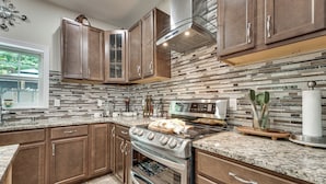A modern kitchen with granite countertops, stainless steel appliances, and wooden cabinetry. - Patio, Porch + Fire Pit! Family Home By Branson (Rockaway Beach)