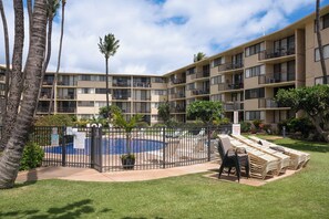 A hotel with a swimming pool surrounded by a fence, multiple balconies, and a well-maintained lawn. - Ocean-view Balcony! Walk to Maalaea Harbor (Wailuku)