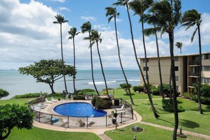 A pool area with a circular pool, palm trees, and a view of the ocean. - Ocean-view Balcony! Walk to Maalaea Harbor (Wailuku)