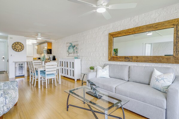 A living room with a sofa, a glass coffee table, and a dining area with chairs and a table. - Ocean-view Balcony! Walk to Maalaea Harbor (Wailuku)