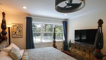 Quarto com cama, cômoda, televisão e janela com cortinas.