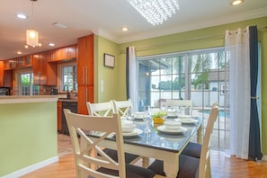 Cozinha moderna com armários de madeira e área de jantar com mesa e cadeiras de vidro.