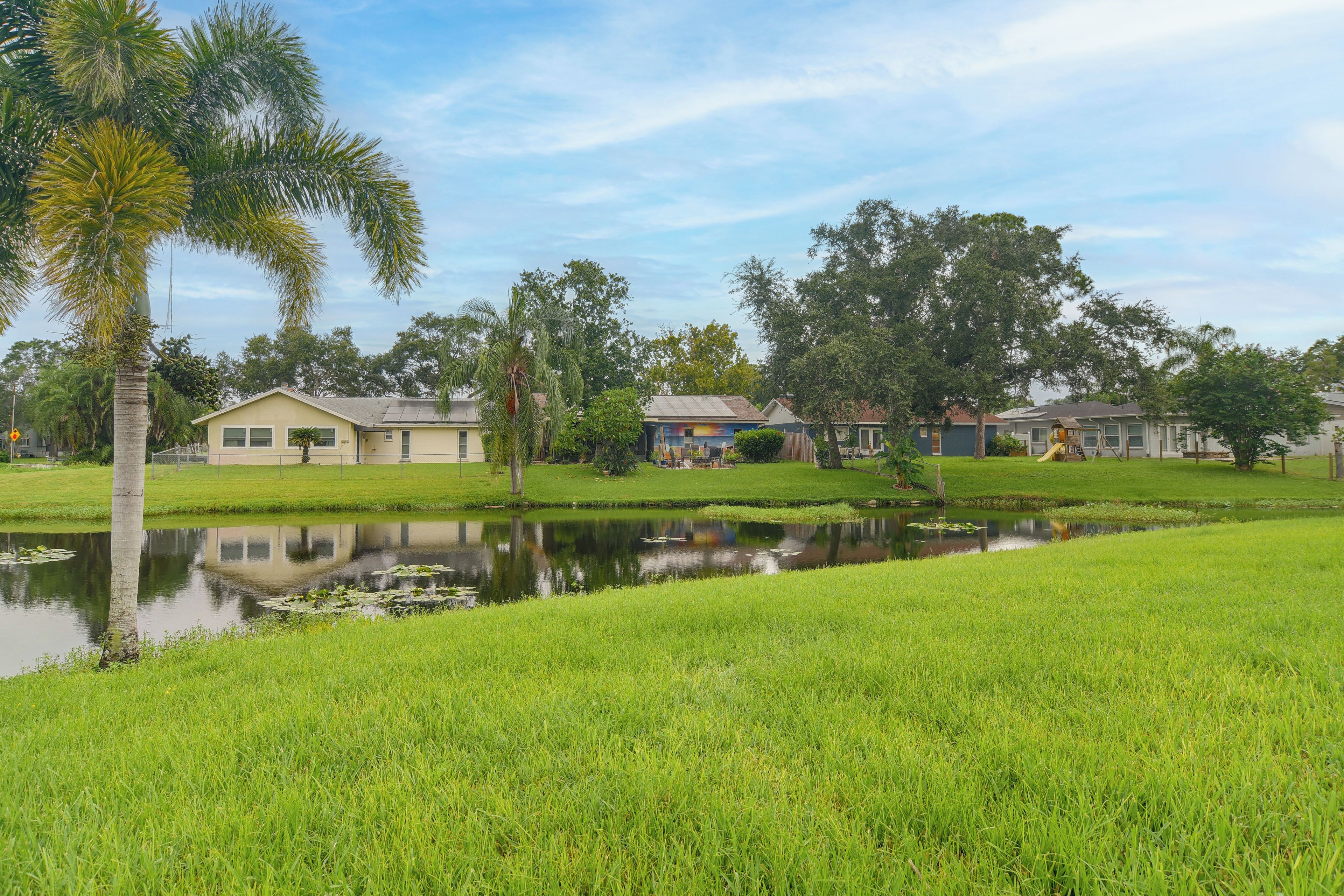 A residential area with houses, a pond, and a grassy field.