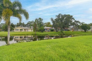 Zona residencial con casas, un estanque y un campo cubierto de césped.