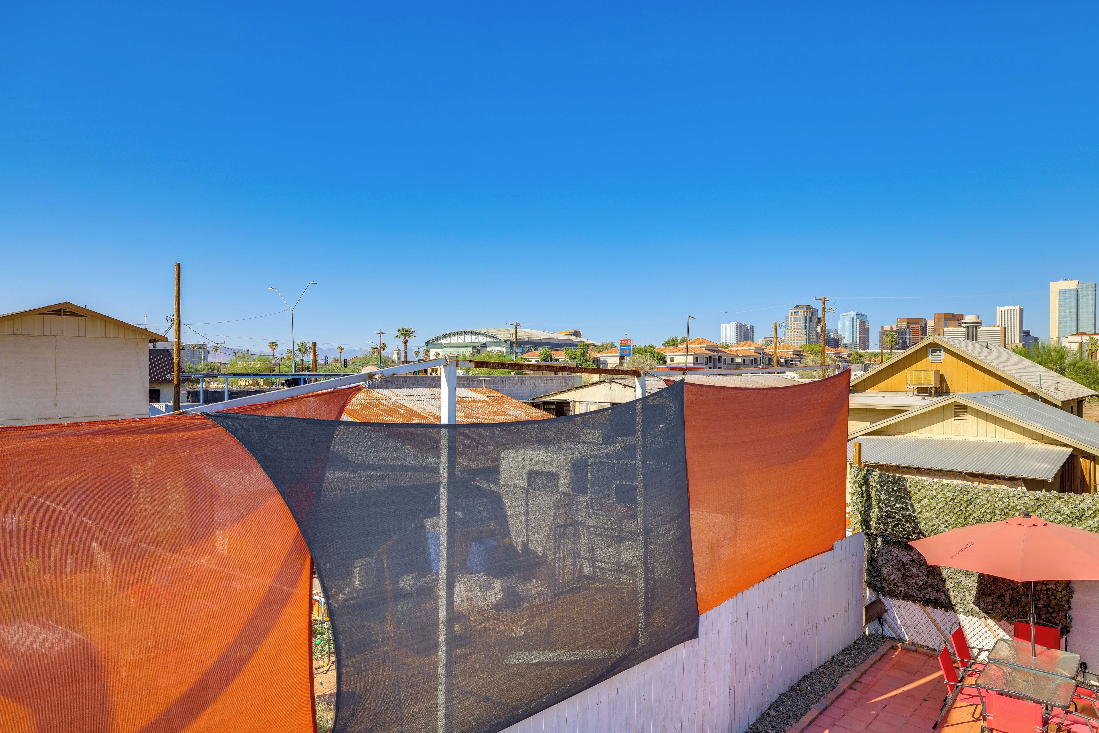 Un patio en la azotea con vistas al horizonte de la ciudad, incluyendo un estadio y edificios altos.