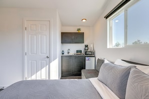 Una habitación pequeña con cama, kitchenette y ventana.