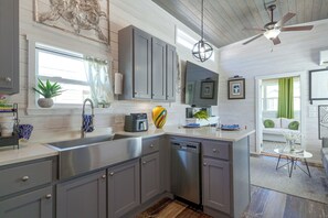A modern kitchen with grey cabinets, a dishwasher, and a ceiling fan.