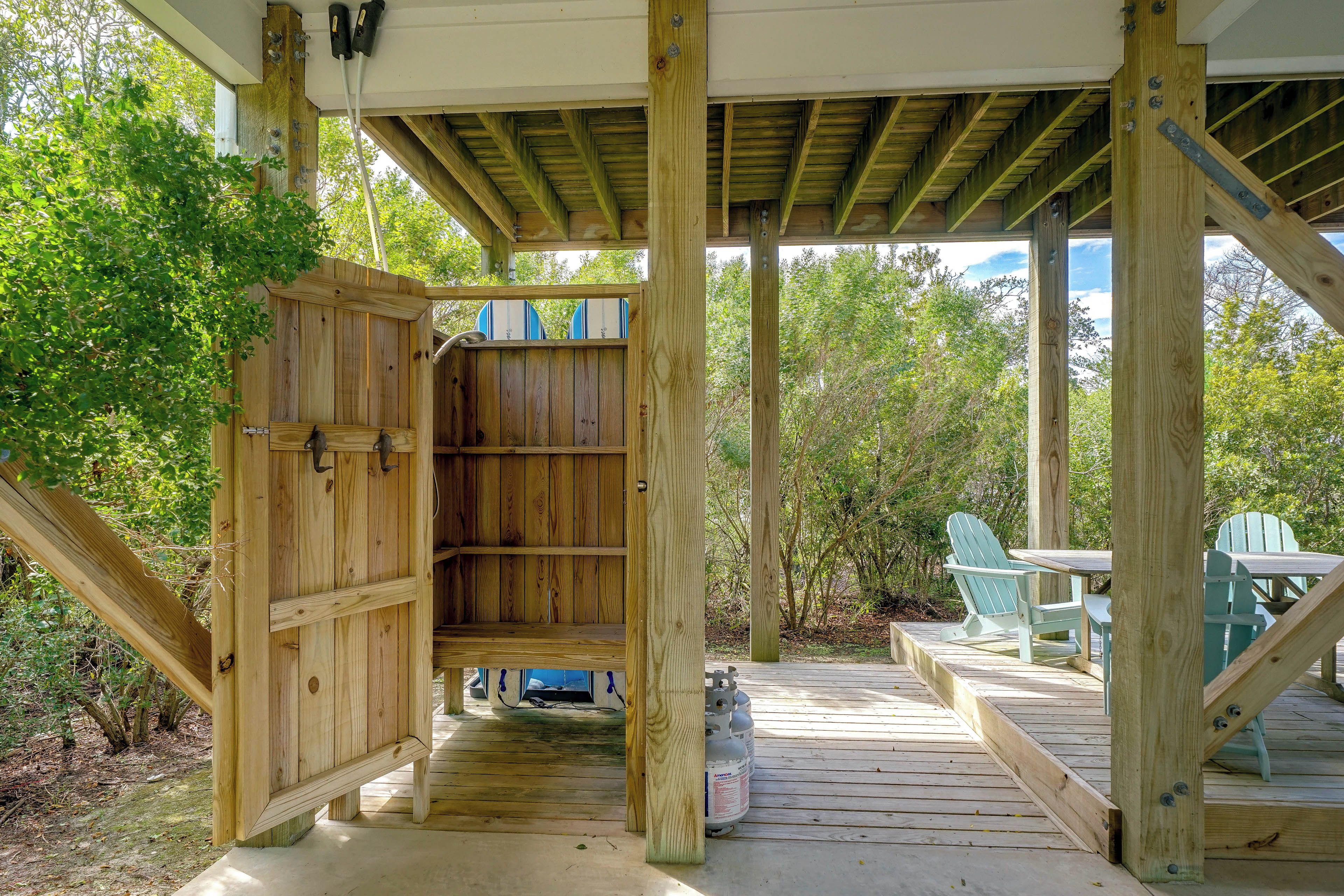 A wooden deck with a covered area, a seating arrangement, and a view of the surrounding greenery.