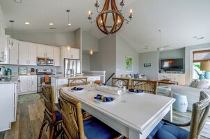 Una cocina moderna con armarios blancos, electrodomésticos de acero inoxidable y una isla central con asientos.