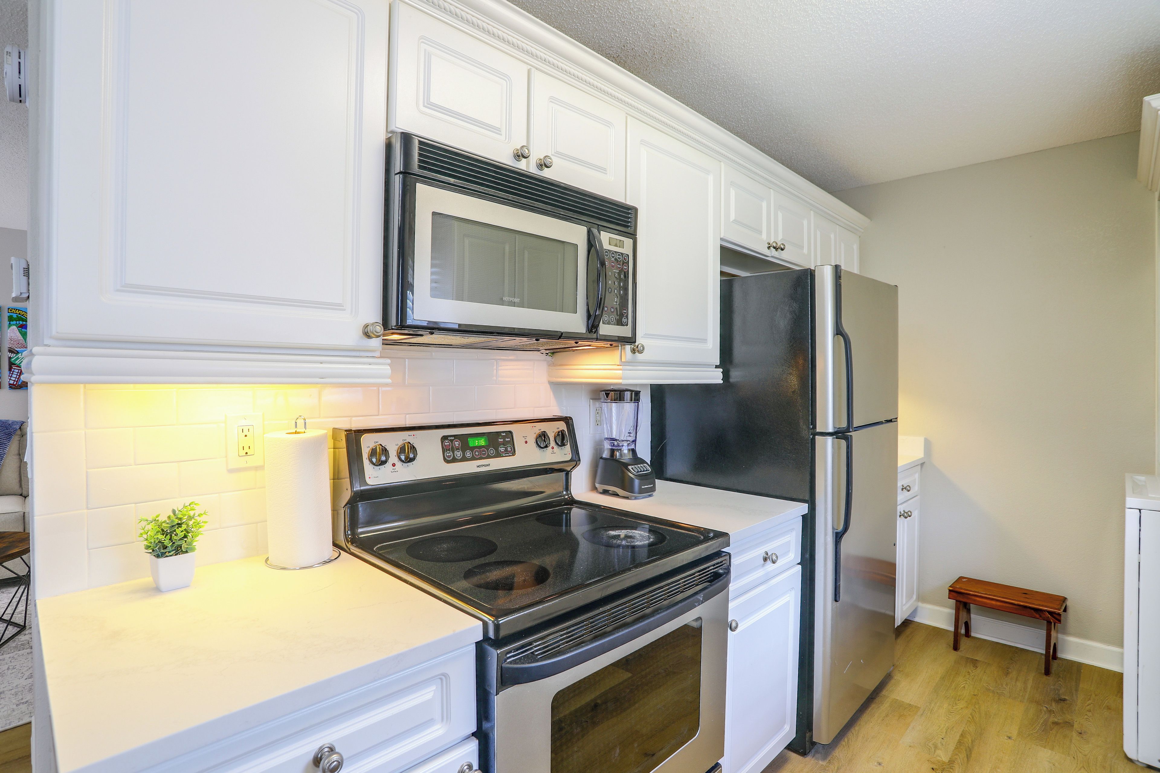 A kitchen with white cabinets, a stainless steel refrigerator, a microwave, and a stove.