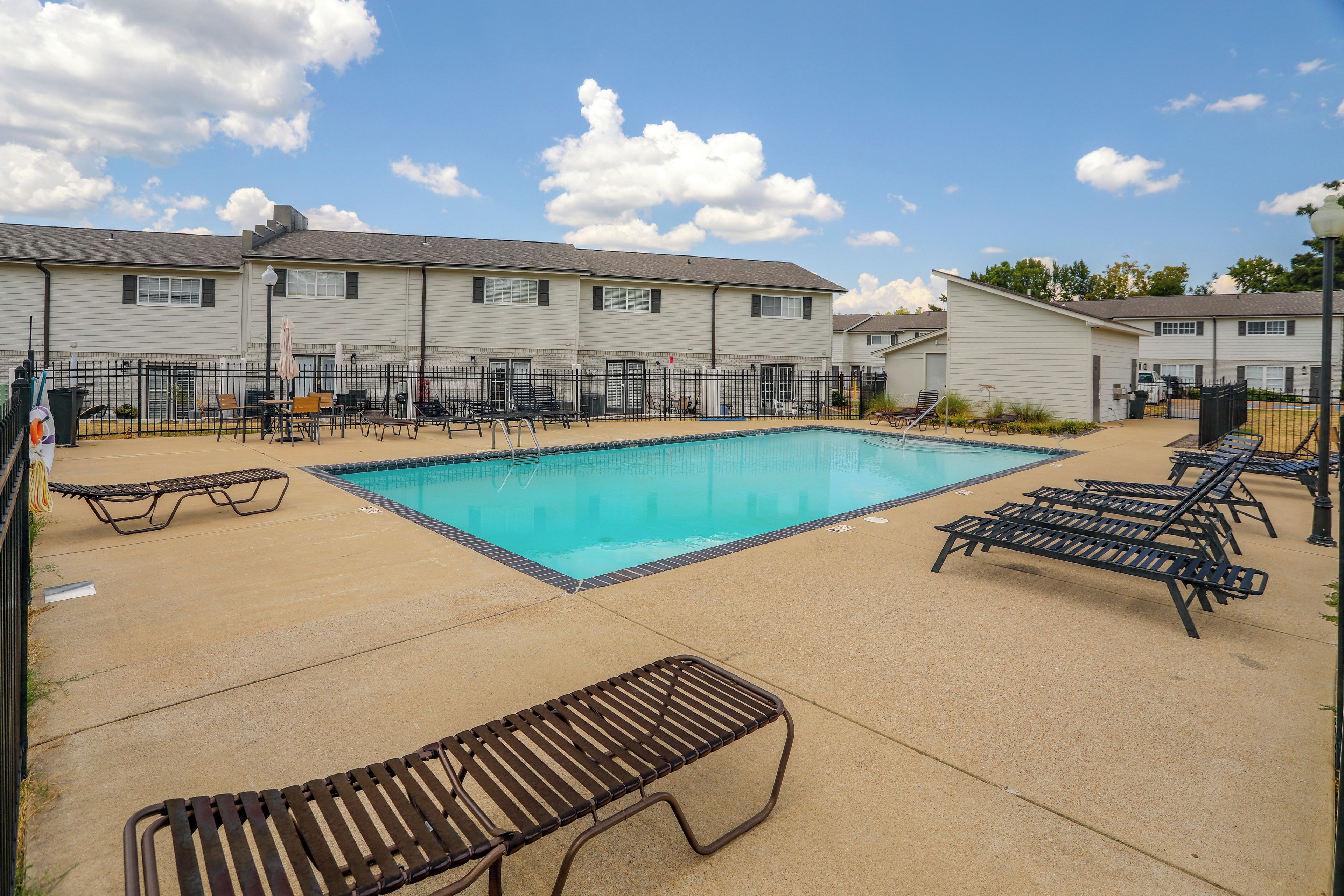 A swimming pool area with lounge chairs and a building in the background.