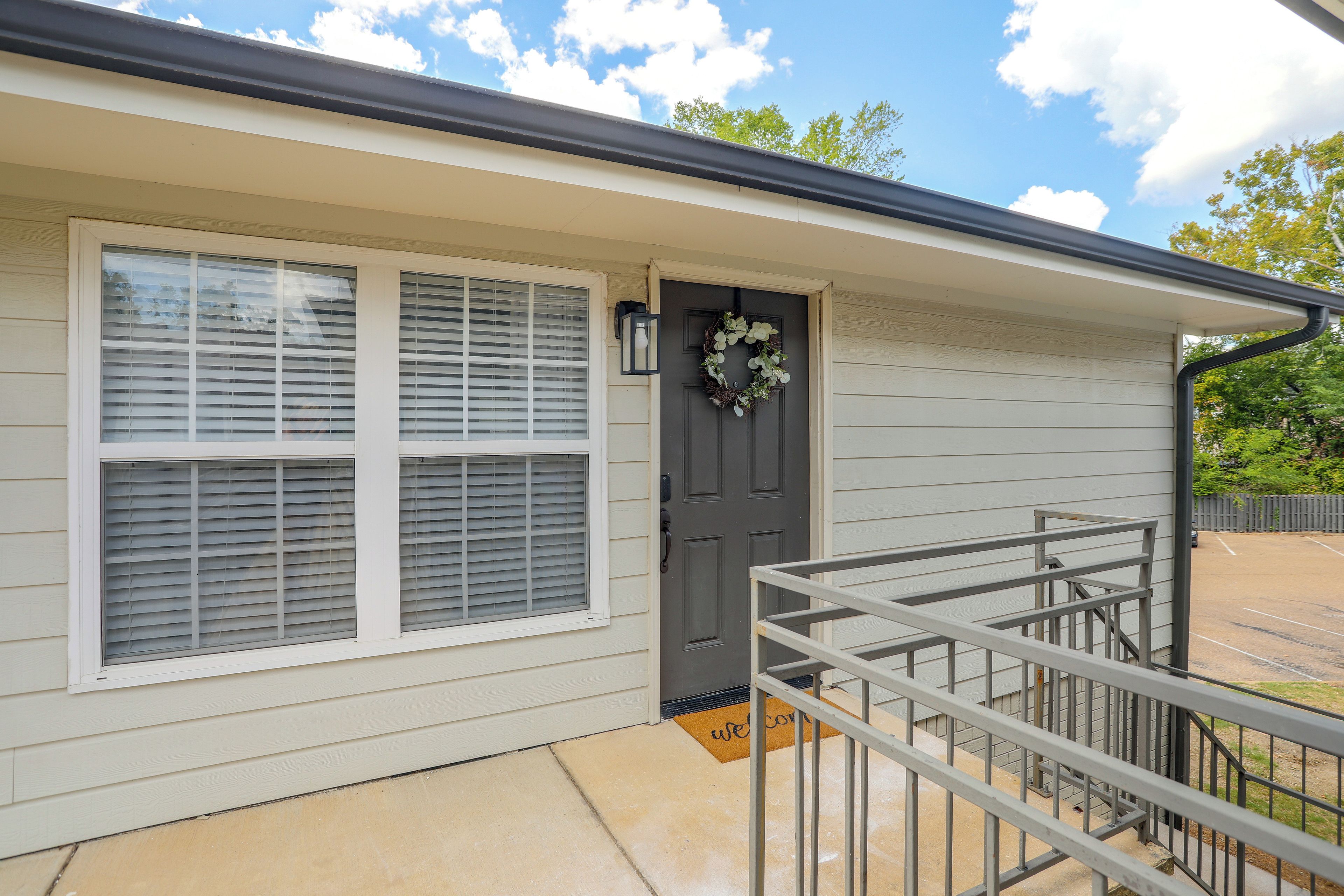 A house with a dark front door, a welcome mat, and a metal railing.