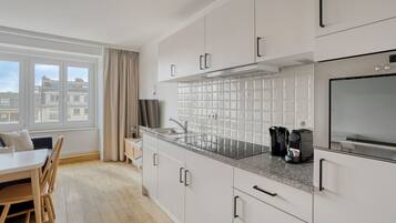 A modern kitchen with white cabinetry, a granite countertop, and a window with a view of buildings.