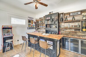 Un espace bar avec un comptoir en bois, des tabourets et un ventilateur de plafond.