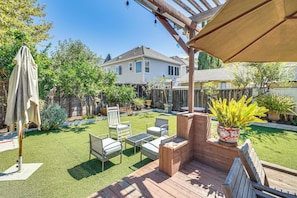 Un jardin avec une terrasse en bois, du mobilier d’extérieur et une pergola.