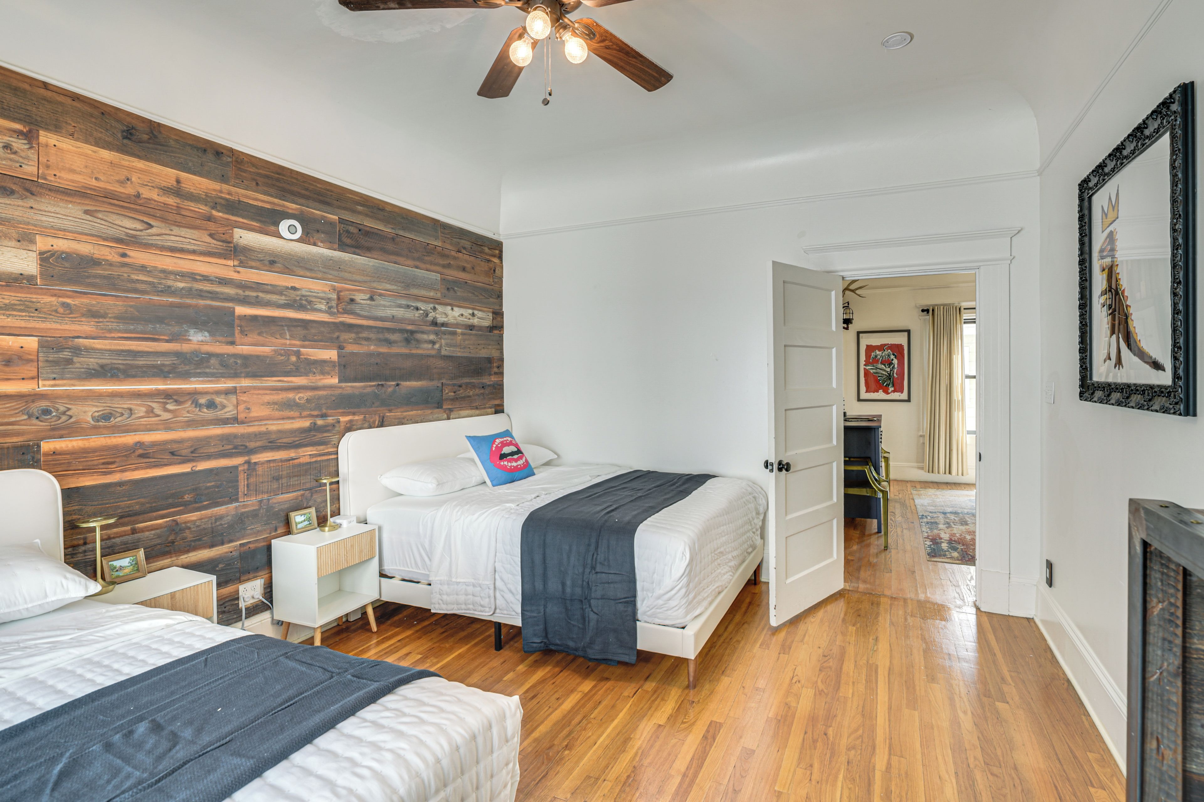 A bedroom with a wooden accent wall, a ceiling fan, and a bed with a blue pillow.