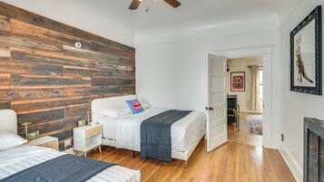 A bedroom with a wooden accent wall, a ceiling fan, and a bed with a blue pillow.
