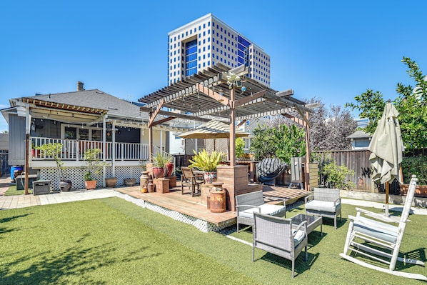 A backyard with a pergola, outdoor furniture, and a barbecue area.