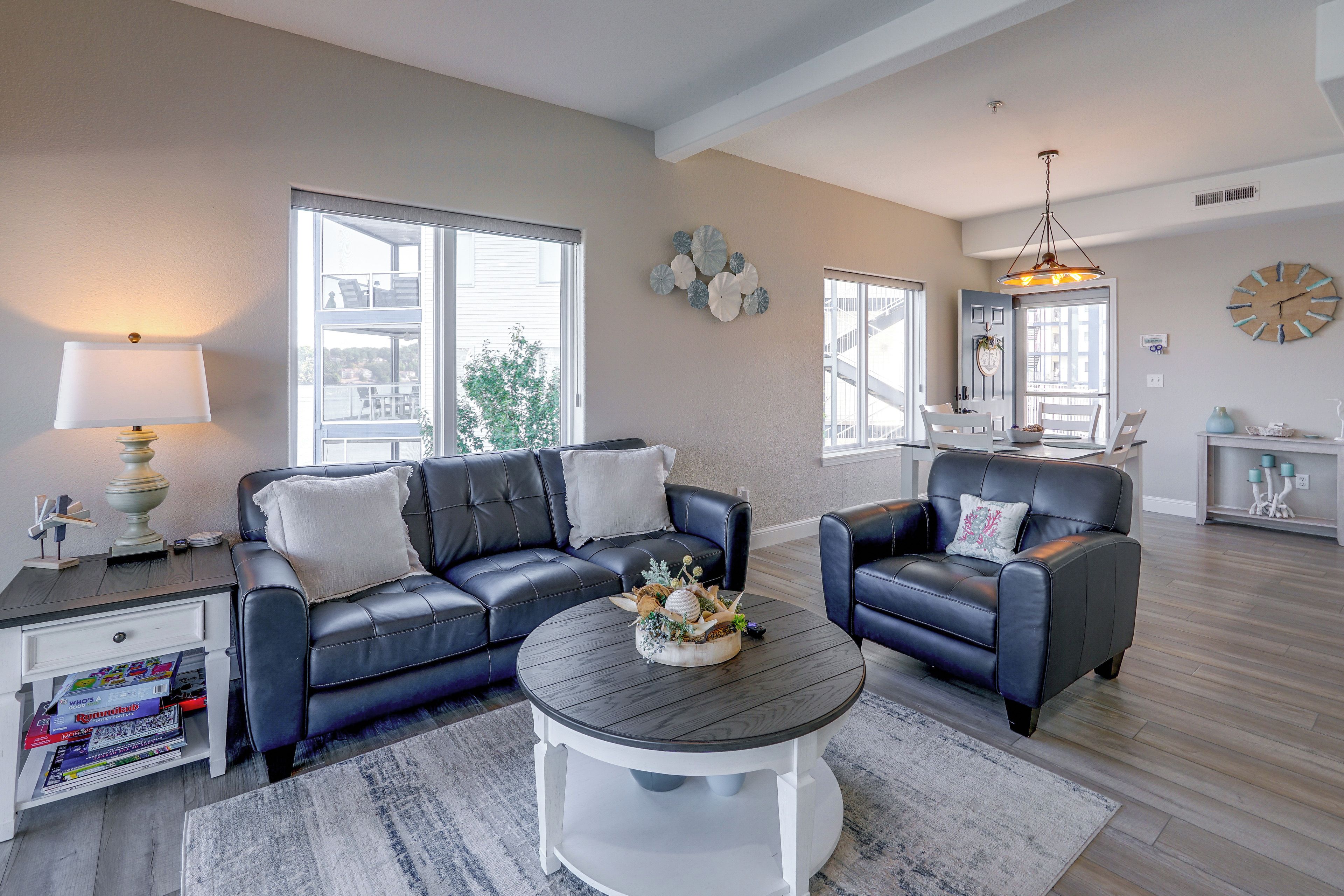 A modern living room with a sectional sofa, a round coffee table, and a dining area with a chandelier.