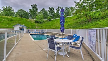 Un espace aménagé au bord de la piscine, comprenant une piscine, des chaises longues et une table avec un parasol.
