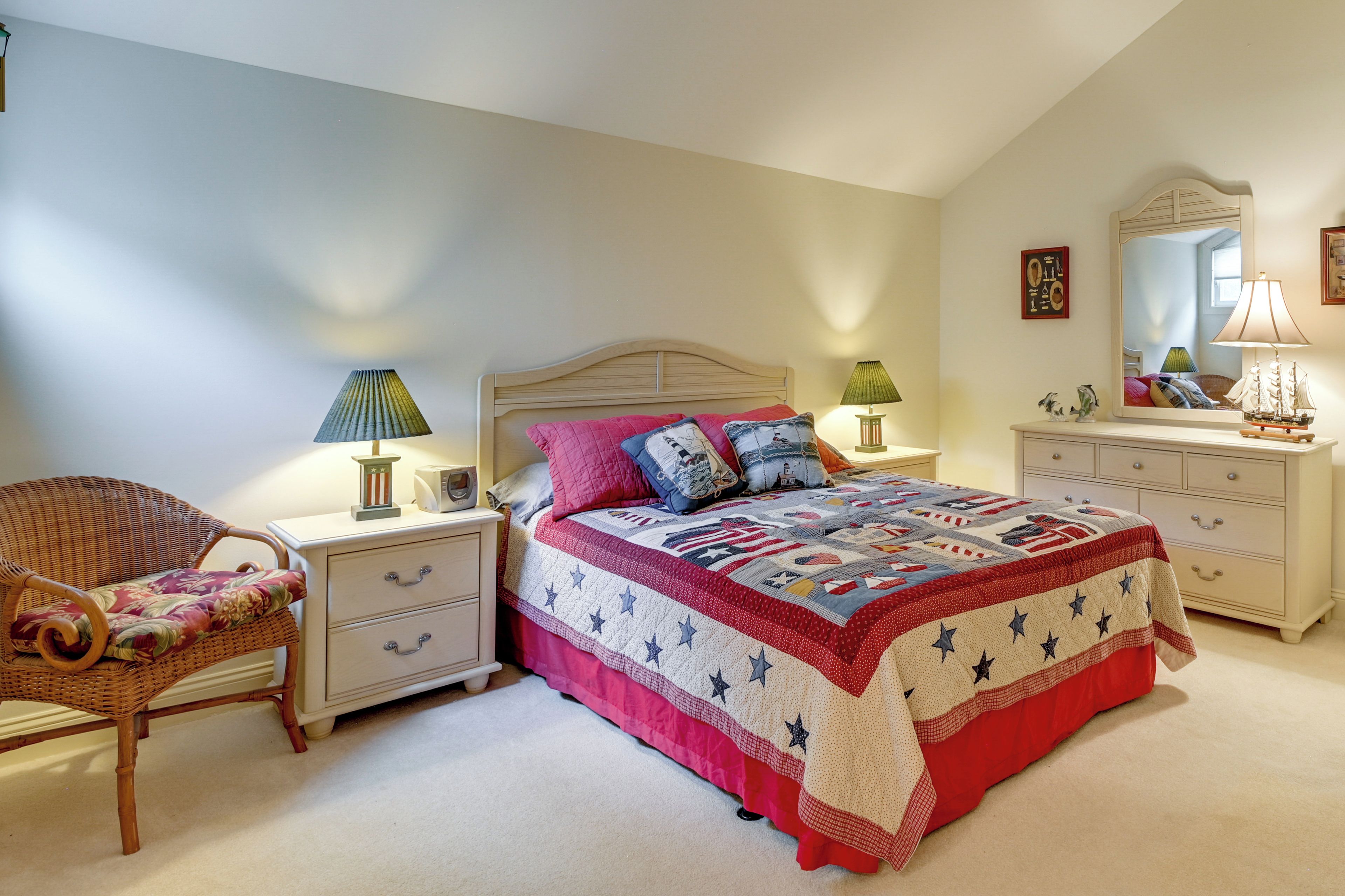 A bedroom with a bed, nightstands, a chair, a dresser, and a mirror.
