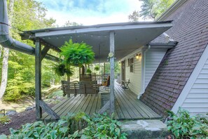 A wooden deck with a covered porch, a bench, and a hanging plant.