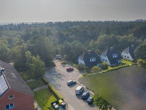 A residential area with detached houses, a parking lot, and a body of water in the background. - Ground Floor in the Reimer House (St. Peter-Ording)