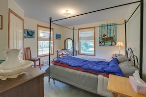 A bedroom with a four-poster bed, a desk with a chair, a dresser, and a window with a view of trees. - 21 Acres, Near Trails to Shore With Island Access (Lubec)