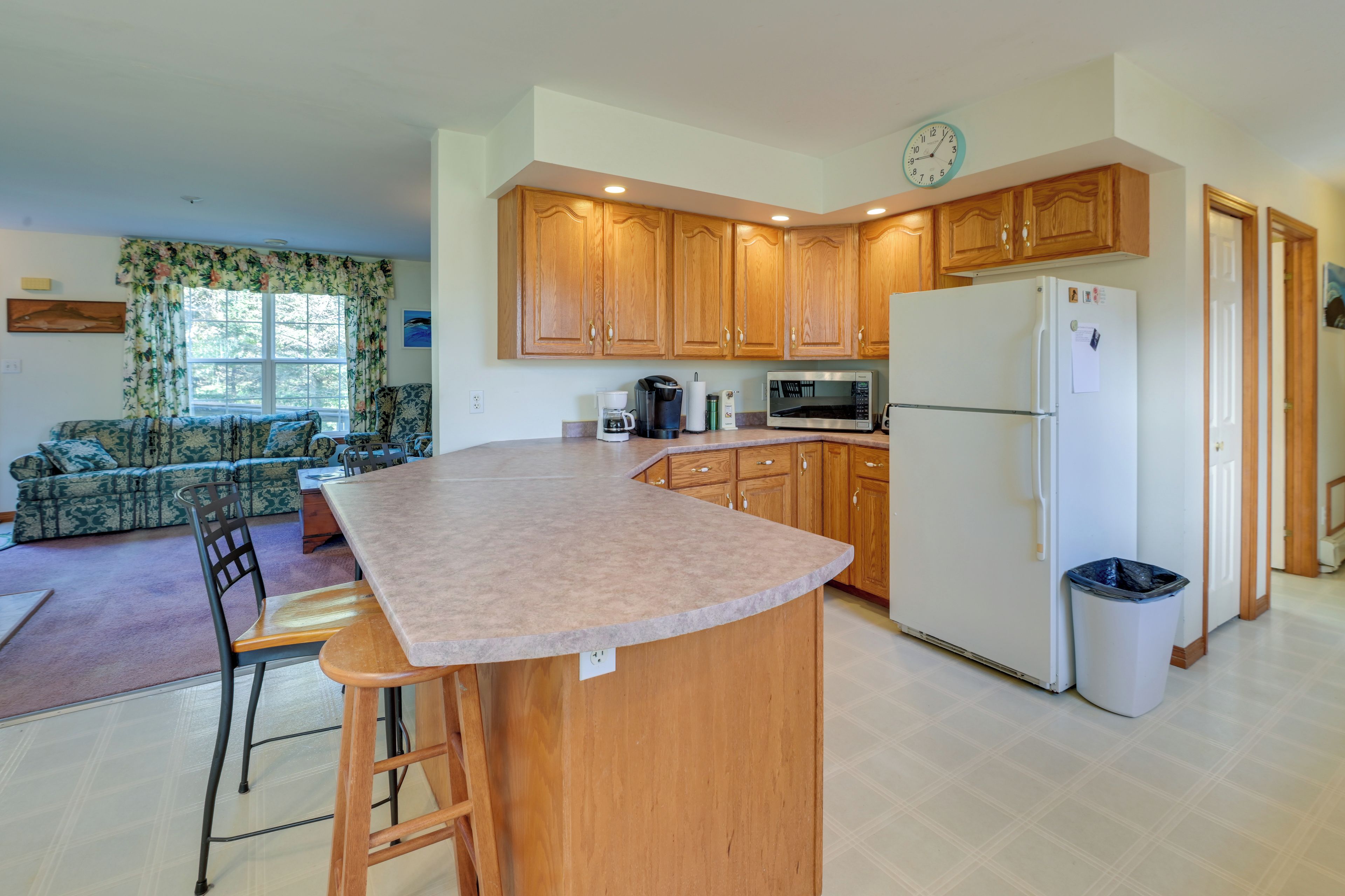 A kitchen with wooden cabinets, a refrigerator, a microwave, and a coffee maker.
