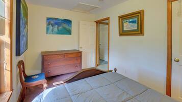 Quarto com cama, penteadeira, cadeira e duas pinturas na parede.