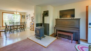 A living room with a fireplace, a dining area with chairs, a television, and a large window.