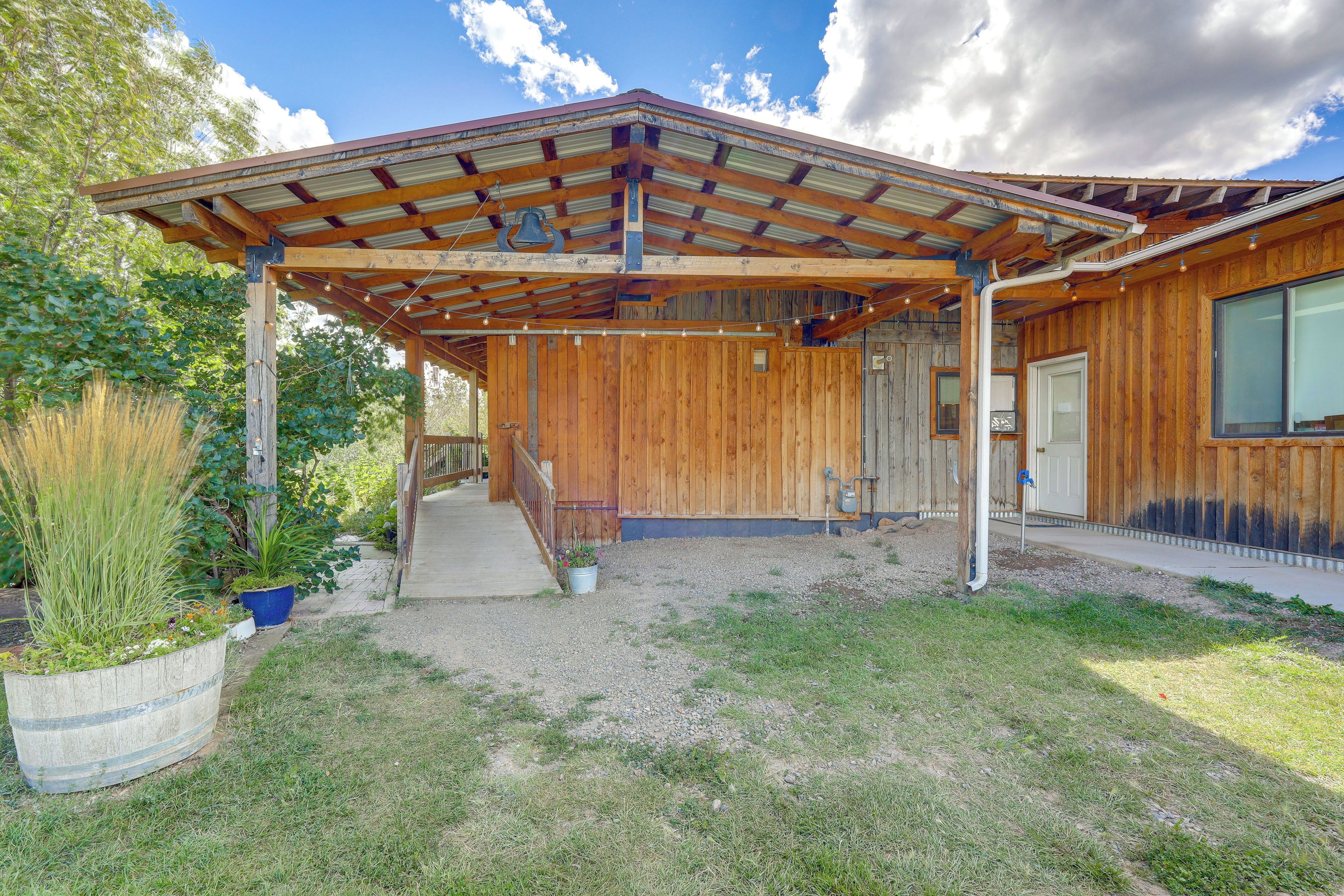 A wooden building with a covered porch, a gravel driveway, and a potted plant.