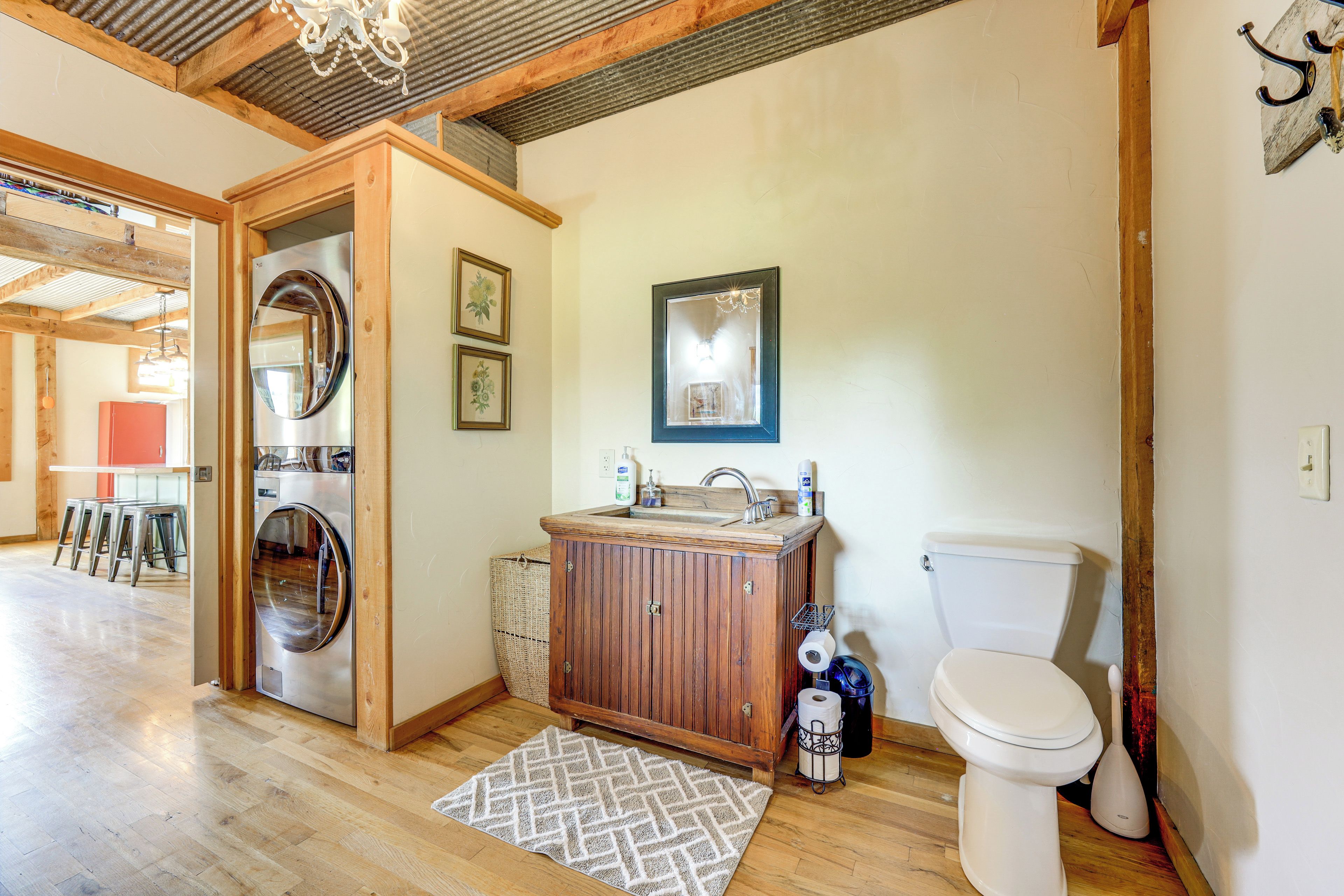 A compact bathroom with a washing machine, wooden cabinet, toilet, and a small sink.