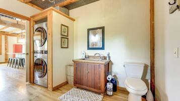 A compact bathroom with a washing machine, wooden cabinet, toilet, and a small sink.