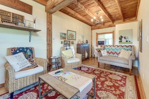 A cozy living room with a wooden ceiling, a sofa, two armchairs, a coffee table, and a rug.