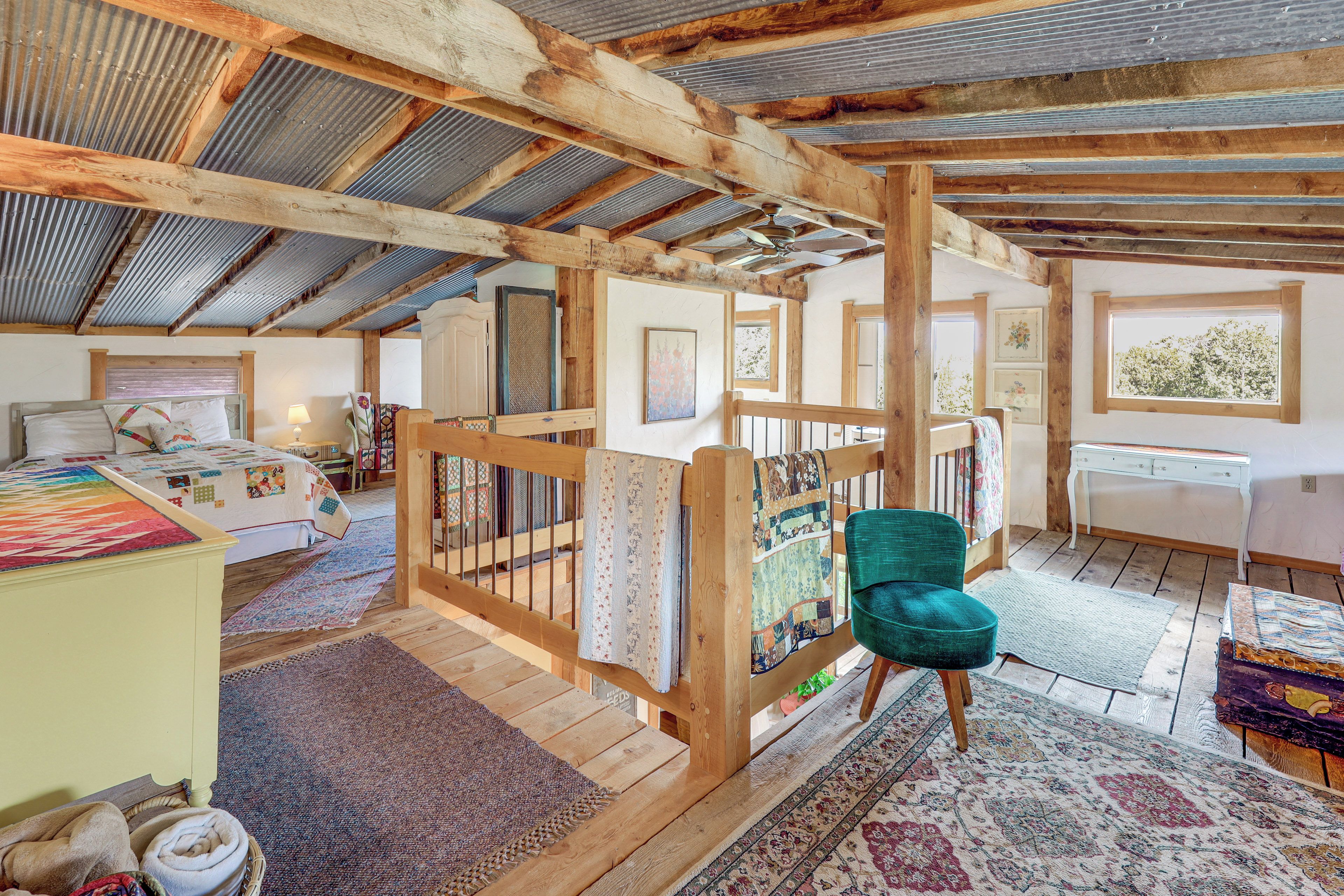 Un dormitorio rústico con una cama de madera, una silla verde y vistas al exterior a través de una ventana.