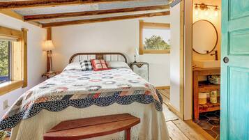 Een slaapkamer met een bed, een bankje, een raam, een lamp, een spiegel en een deur.