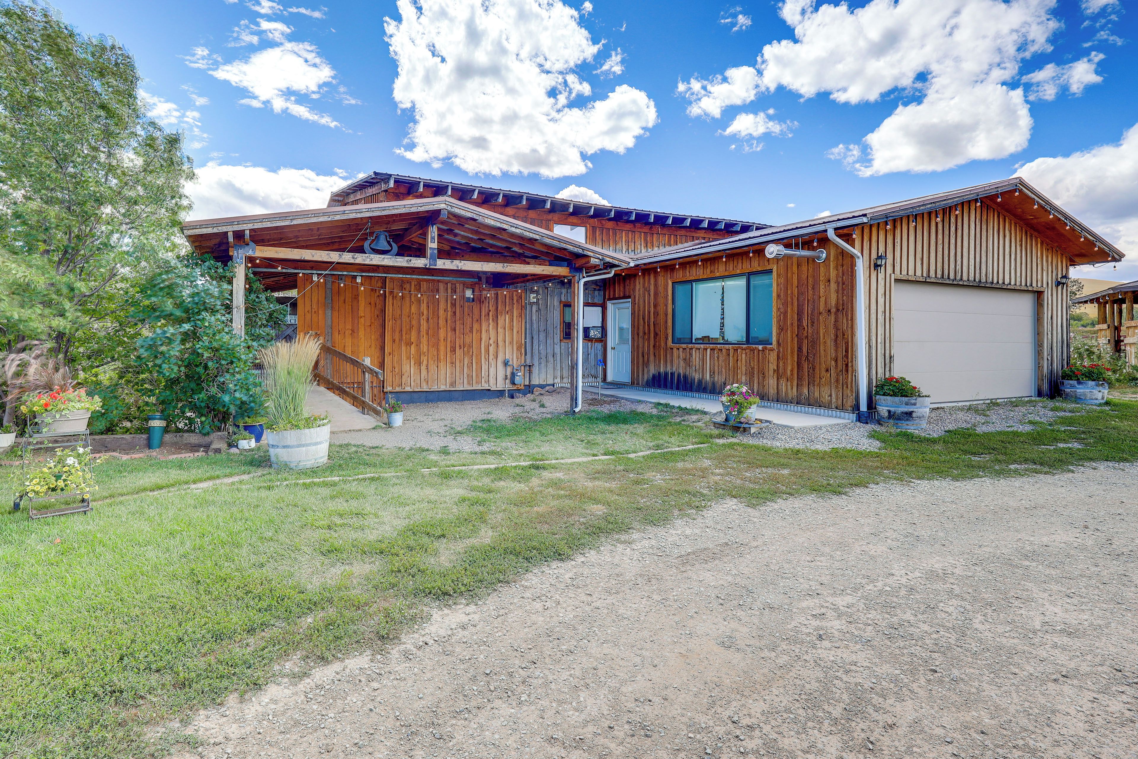 A wooden cabin with a covered porch, a garage, and a gravel driveway.