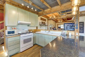 A spacious kitchen with a large island, wooden beams, and a variety of appliances.
