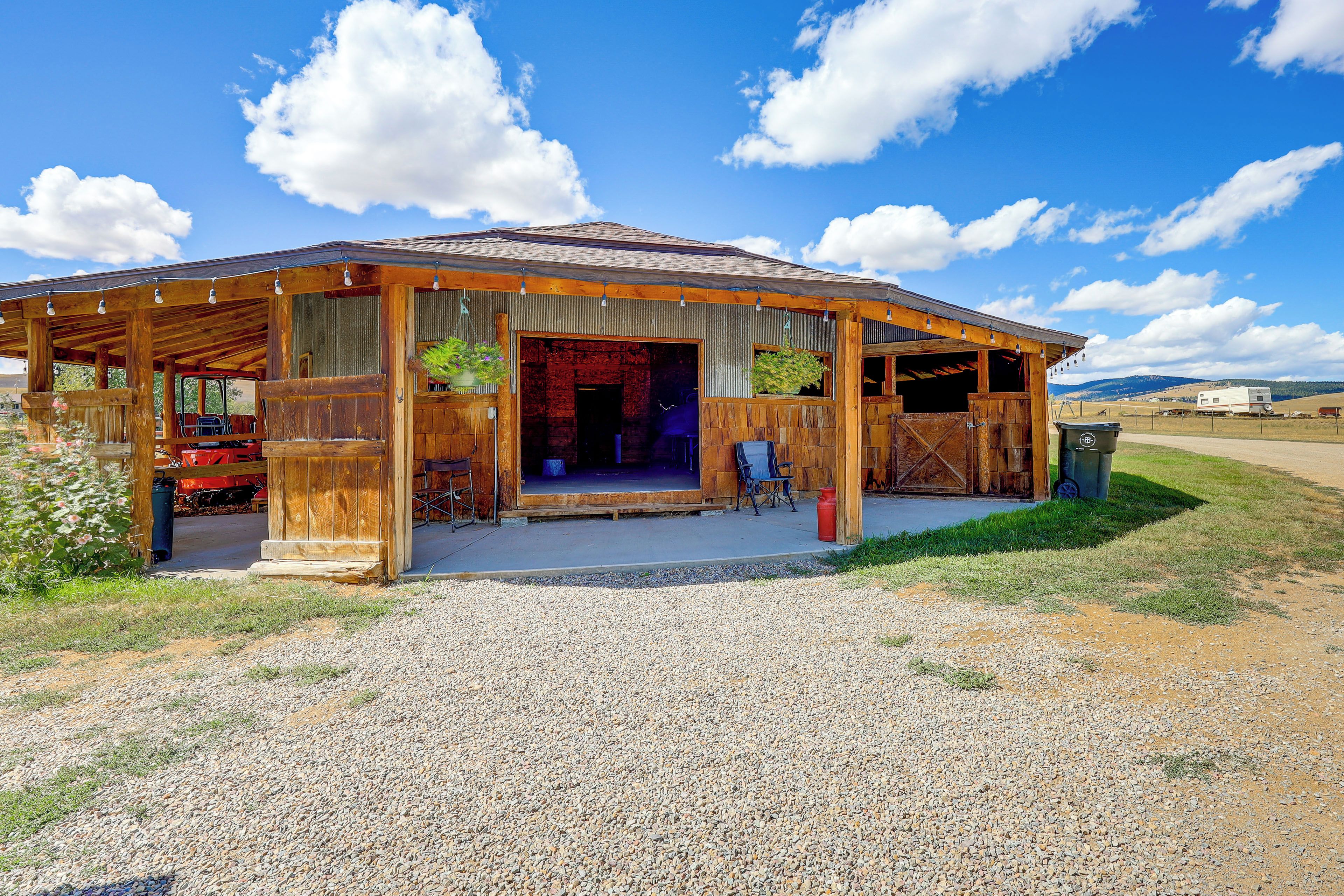 Un edificio de madera rústico con camino de grava, un espacio de estar cubierto al aire libre y un gran ventanal.