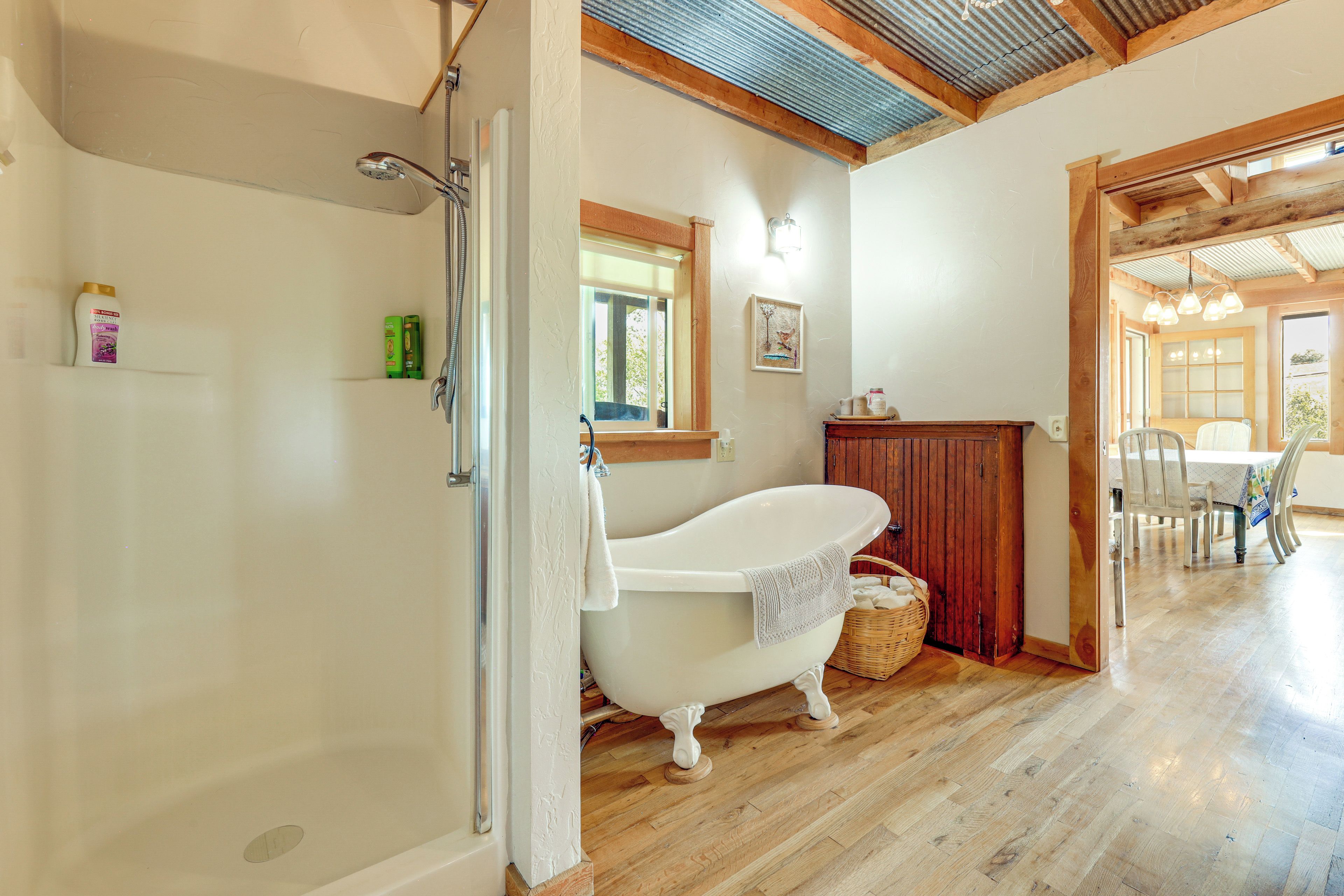 A bathroom with a freestanding bathtub, a shower, and a wooden floor.
